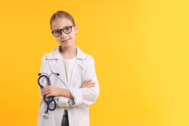 Photo of Girl with stethoscope pretending to be doctor on yellow background, space for text. Dreaming of future profession