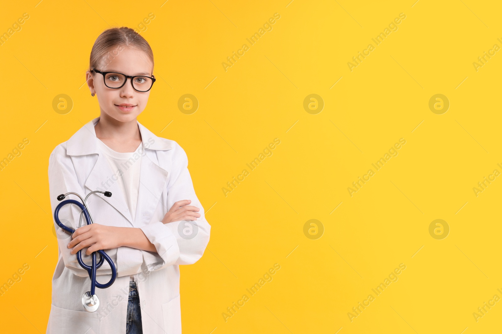 Photo of Girl with stethoscope pretending to be doctor on yellow background, space for text. Dreaming of future profession