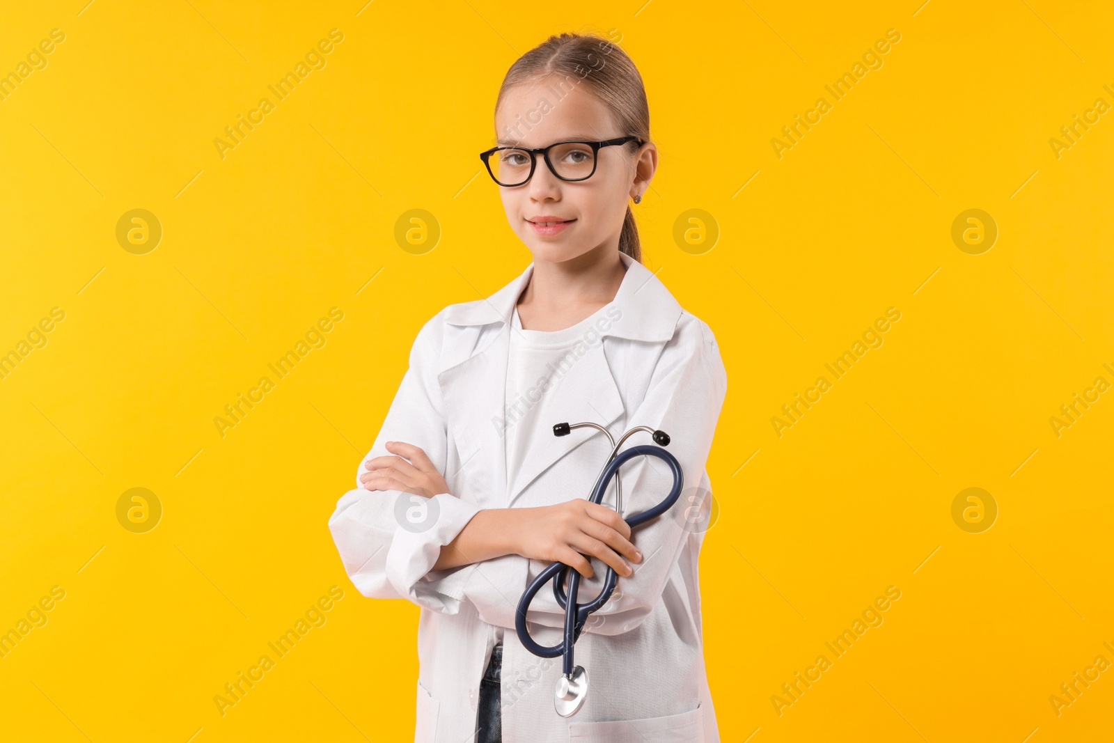 Photo of Girl with stethoscope pretending to be doctor on yellow background. Dreaming of future profession