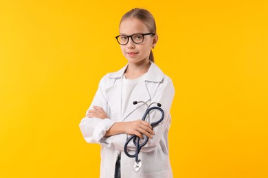 Girl with stethoscope pretending to be doctor on yellow background. Dreaming of future profession