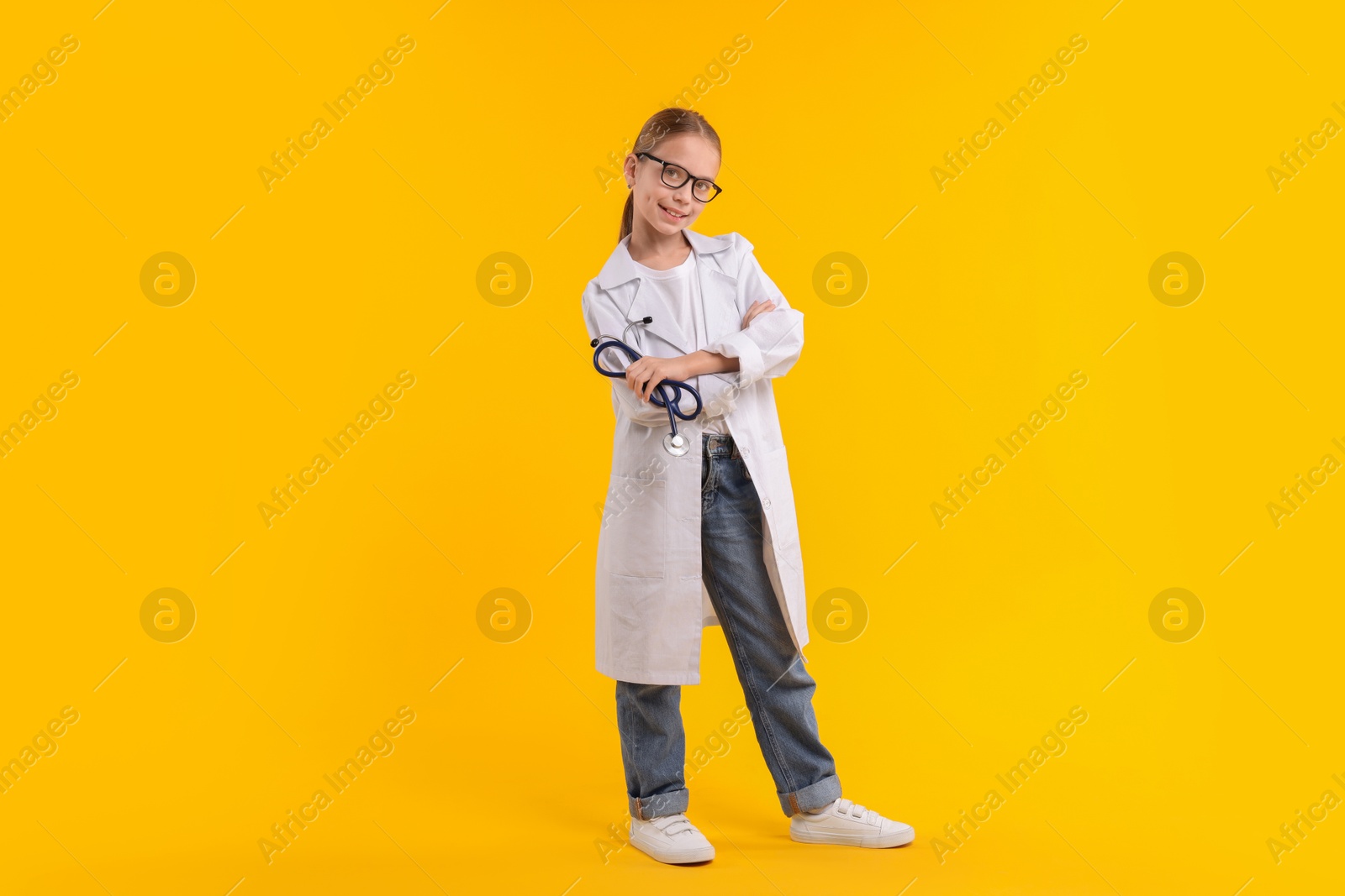 Photo of Girl with stethoscope pretending to be doctor on yellow background. Dreaming of future profession