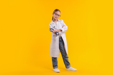 Photo of Girl with stethoscope pretending to be doctor on yellow background. Dreaming of future profession