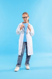 Photo of Girl with stethoscope pretending to be doctor on light blue background. Dreaming of future profession