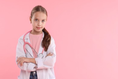 Photo of Girl with stethoscope pretending to be doctor on pink background, space for text. Dreaming of future profession