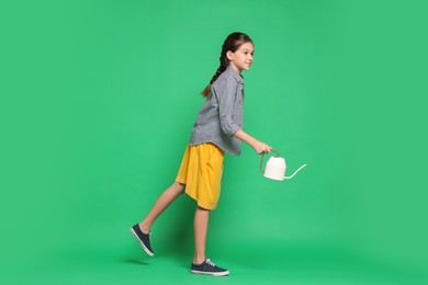 Photo of Girl with watering can pretending to be gardener on green background. Dreaming of future profession