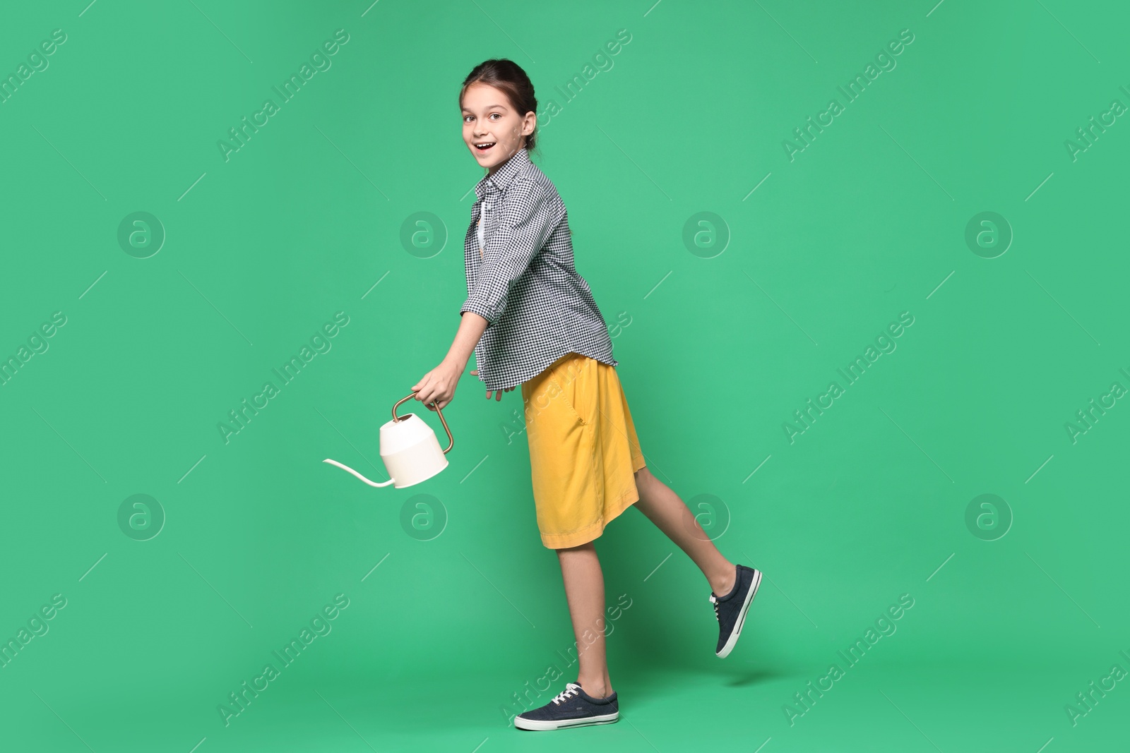 Photo of Girl with watering can pretending to be gardener on green background. Dreaming of future profession