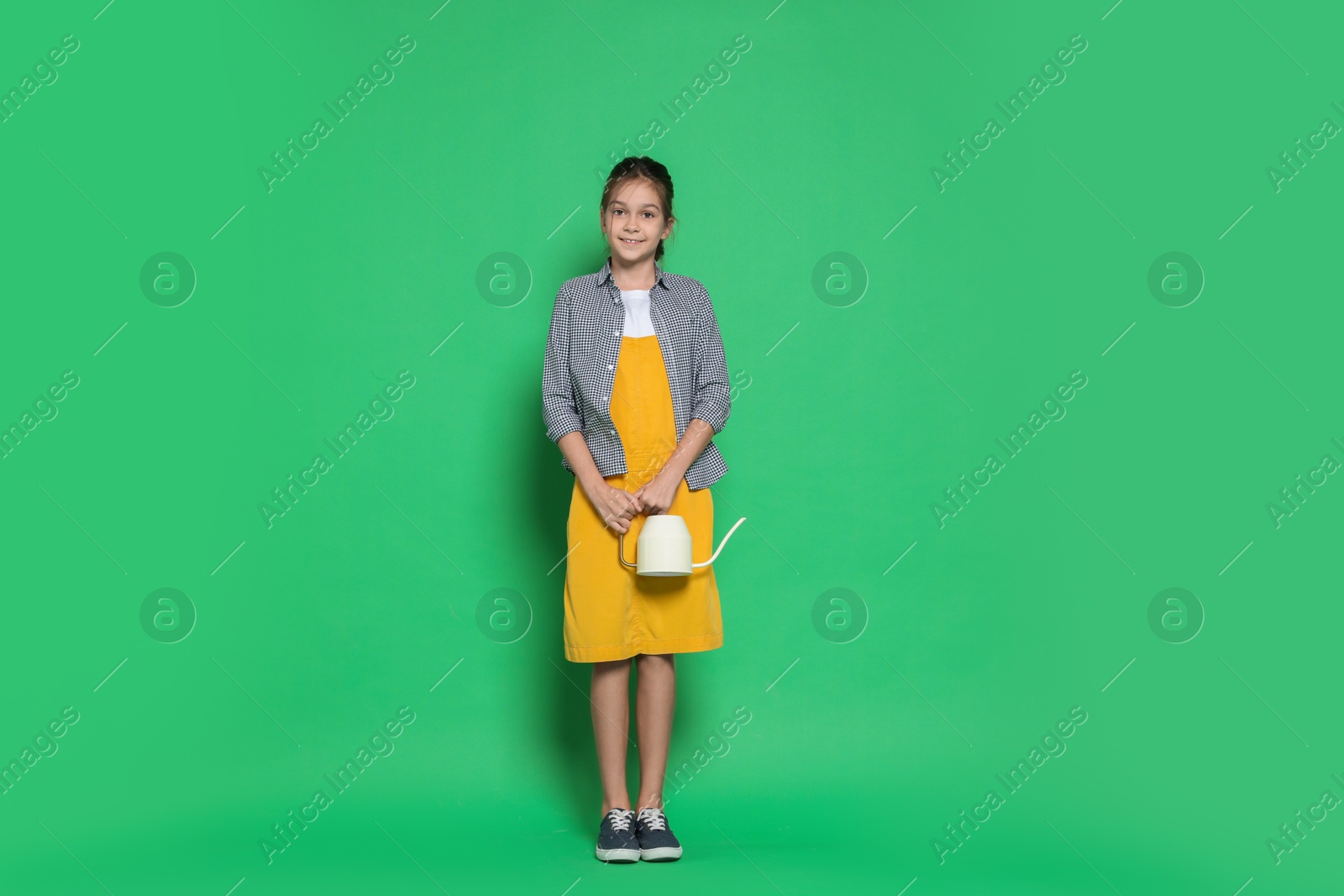 Photo of Girl with watering can pretending to be gardener on green background. Dreaming of future profession