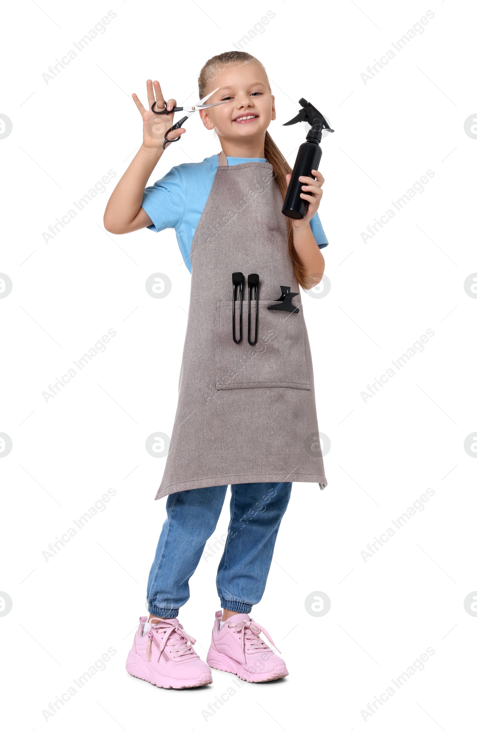 Photo of Little girl with scissors and sprayer pretending to be hairdresser on white background. Dreaming of future profession