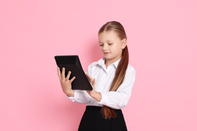 Photo of Little girl with calculator pretending to be accountant on pink background. Dreaming of future profession