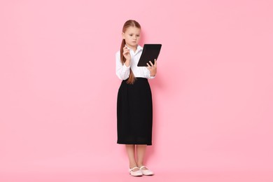 Photo of Little girl with calculator pretending to be accountant on pink background. Dreaming of future profession