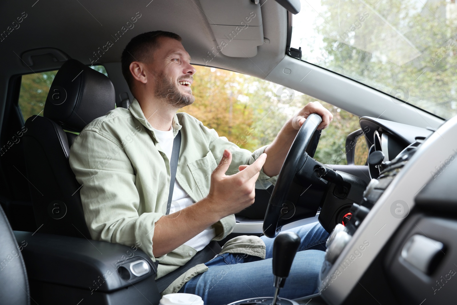 Photo of Happy man behind steering wheel of modern car