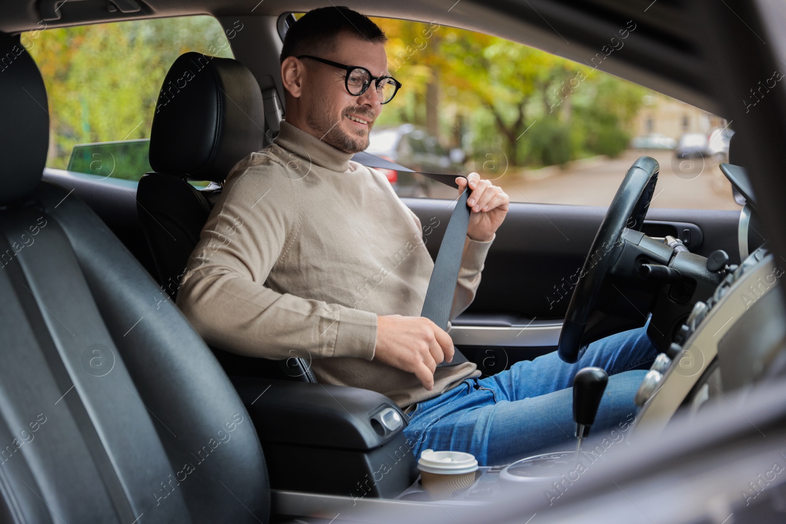 Photo of Man fastening seat belt in modern car