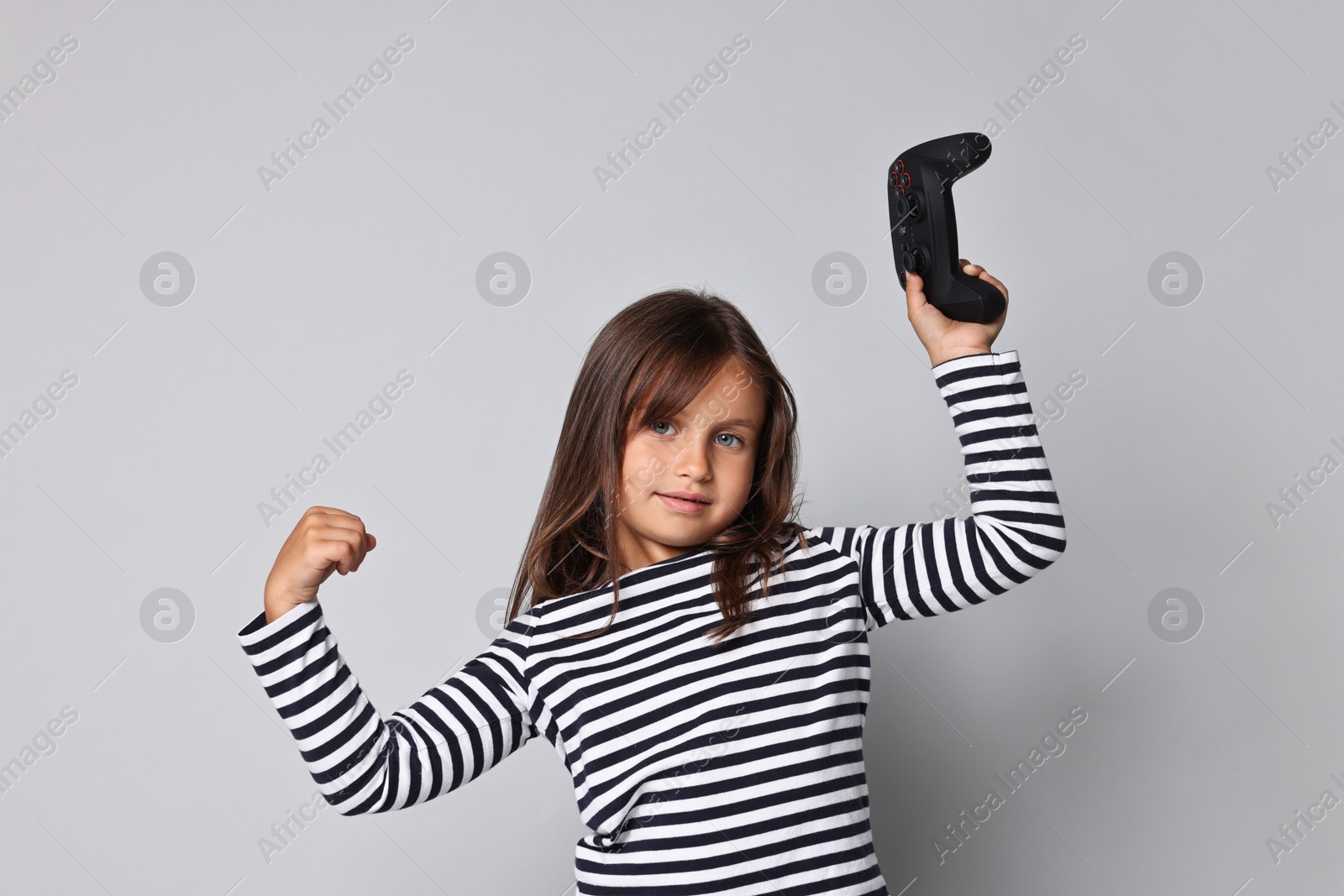 Photo of Cute little girl with controller on grey background