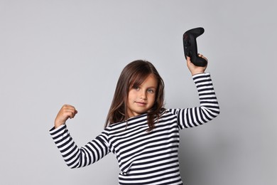 Photo of Cute little girl with controller on grey background