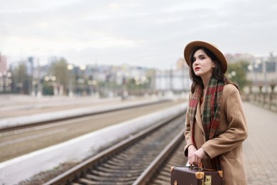 Photo of Beautiful woman with suitcase at railway station