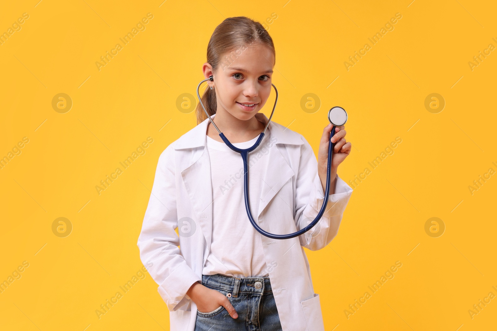 Photo of Girl with stethoscope pretending to be doctor on yellow background. Dreaming of future profession