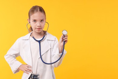 Girl with stethoscope pretending to be doctor on yellow background, space for text. Dreaming of future profession