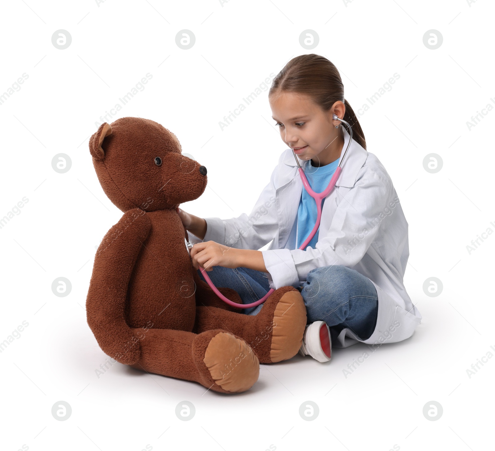 Photo of Girl with stethoscope and toy pretending to be doctor on white background. Dreaming of future profession