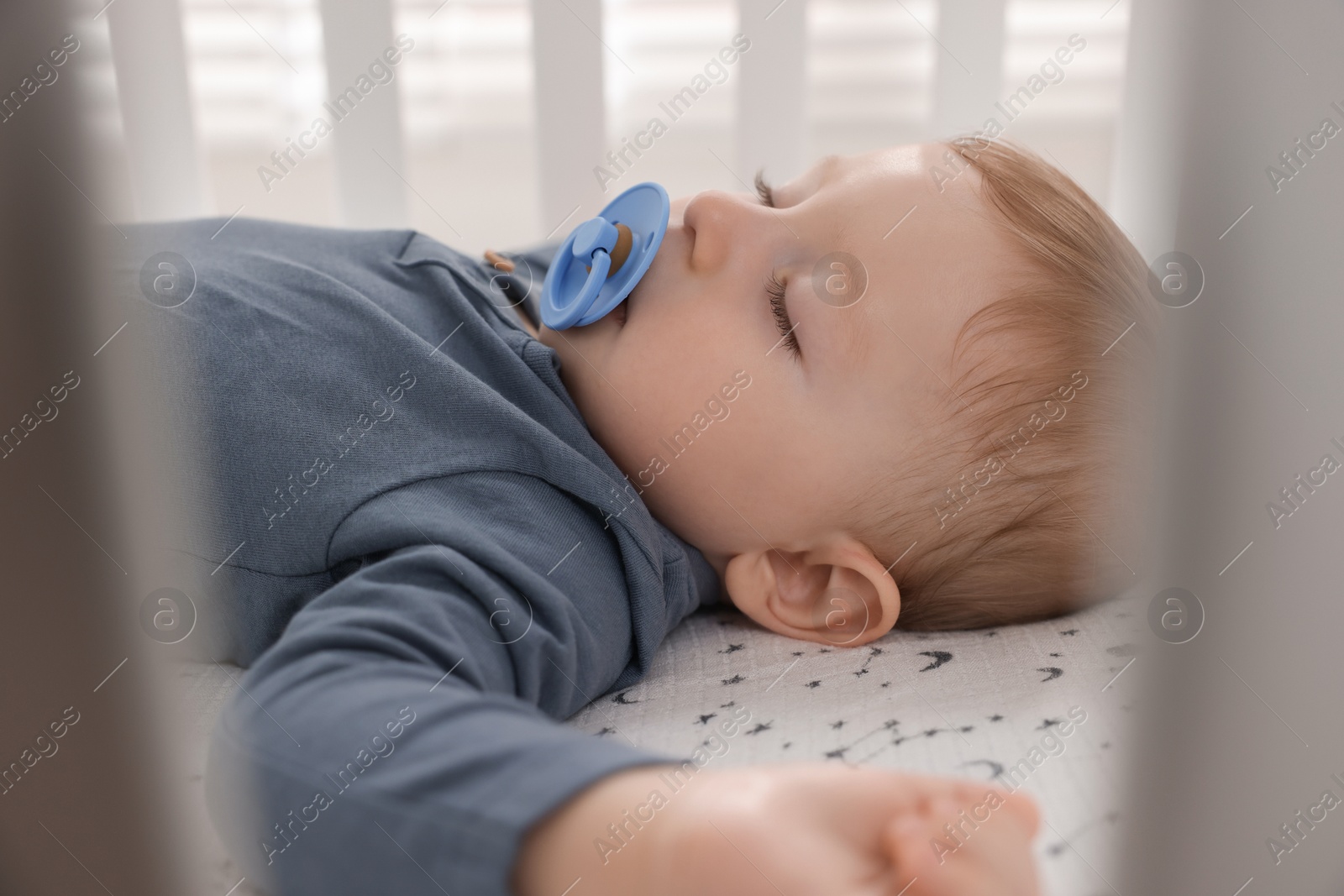 Photo of Cute baby sleeping in crib at home, closeup