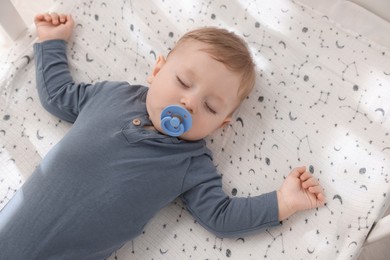 Photo of Cute baby sleeping in crib at home, top view