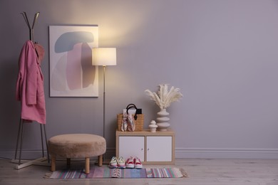 Photo of Stylish hallway interior with pouf and lamp. space for text