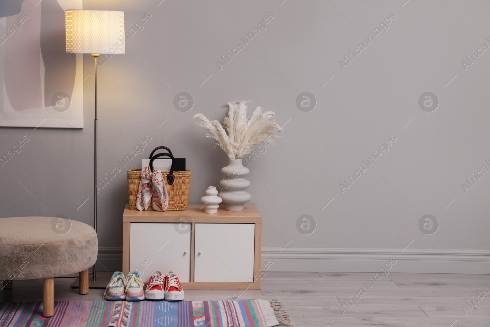 Photo of Stylish hallway interior with pouf and lamp. space for text