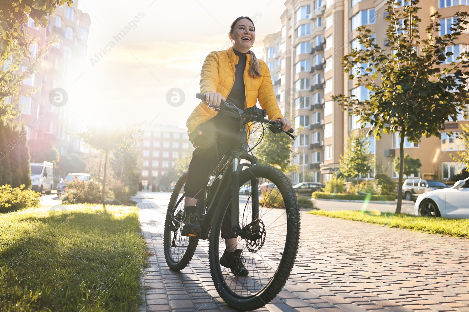 Photo of Smiling woman with bicycle outdoors on sunny day, low angle view