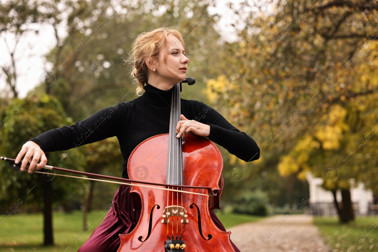 Photo of Beautiful young woman playing cello in park