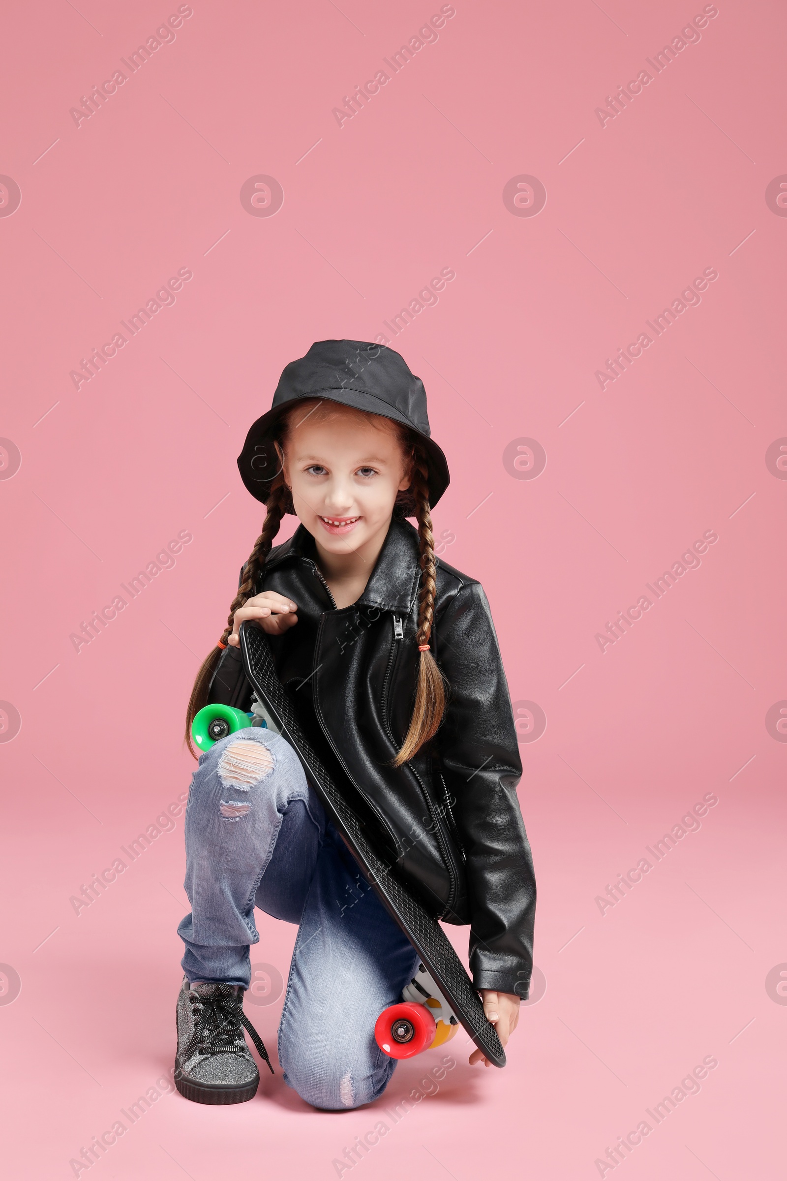 Photo of Little girl with penny board on pink background