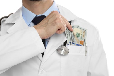 Photo of Corruption concept. Doctor putting dollar banknotes into his pocket on white background, closeup