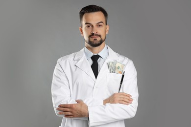 Photo of Corruption concept. Doctor with dollar banknotes on grey background