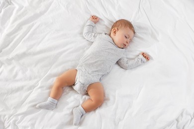 Photo of Cute little baby sleeping on bed at home, top view