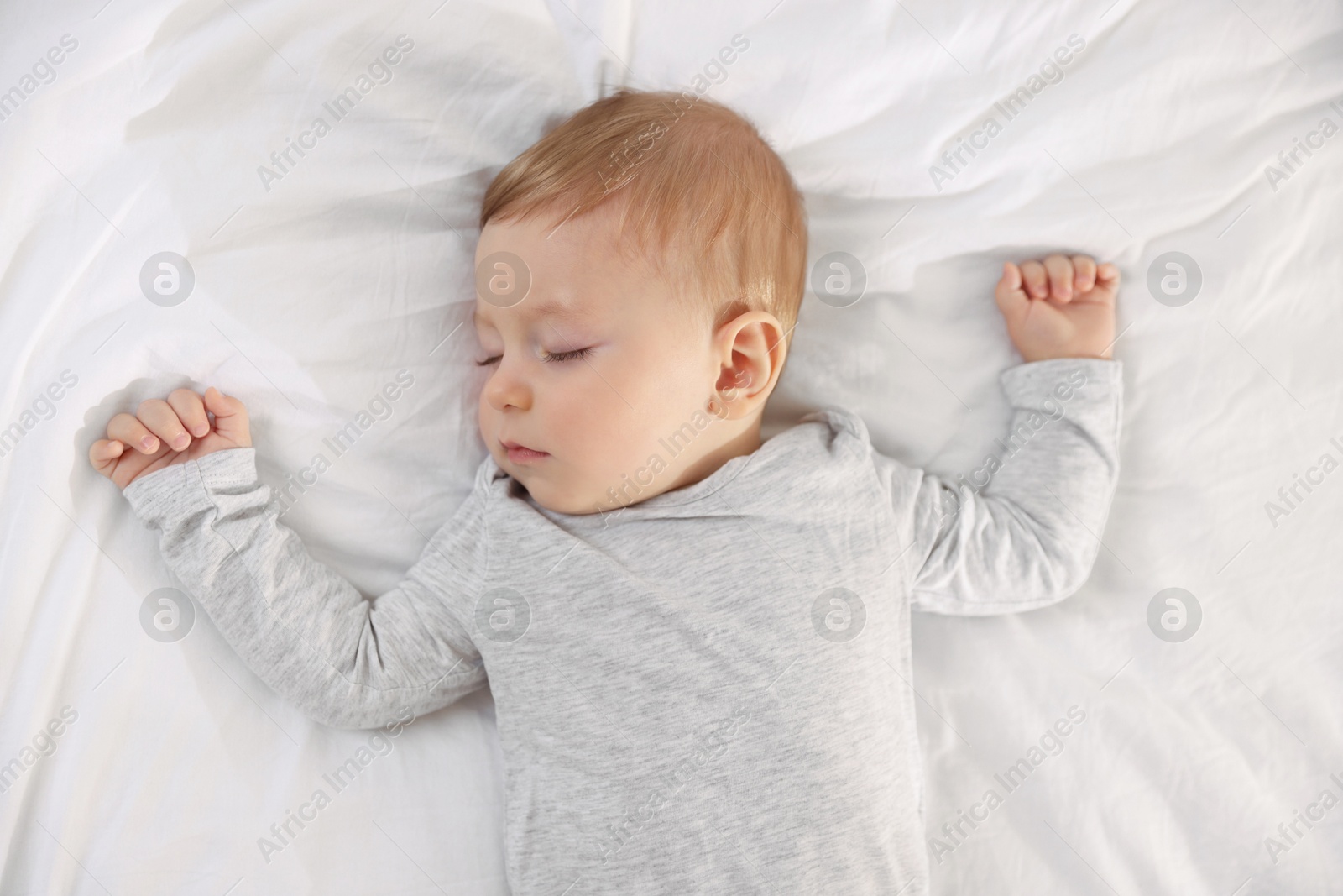 Photo of Cute little baby sleeping on bed at home, top view