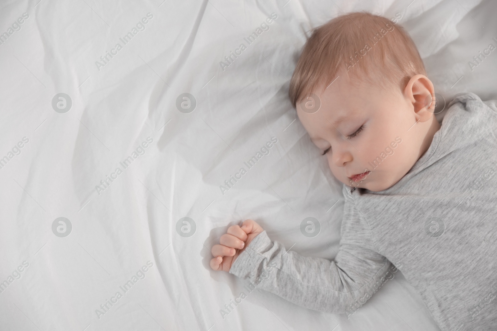 Photo of Cute little baby sleeping on bed at home, top view. Space for text