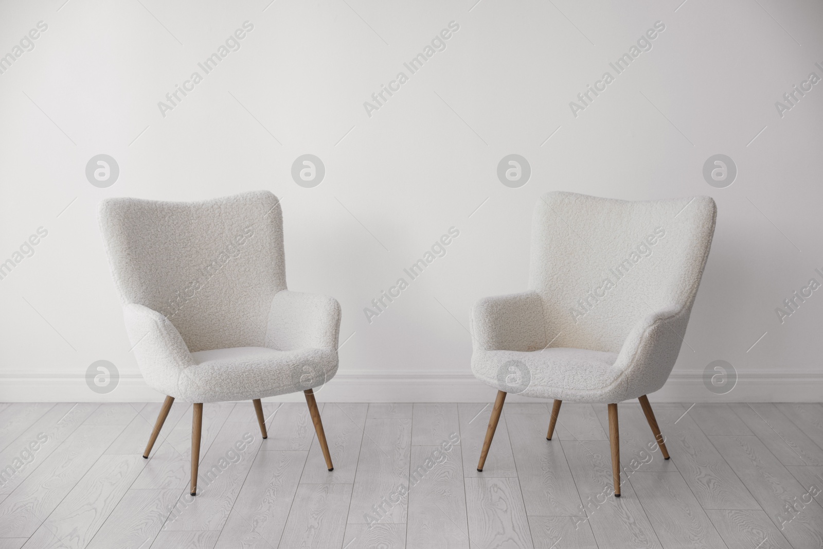 Photo of Stylish soft armchairs near white wall indoors