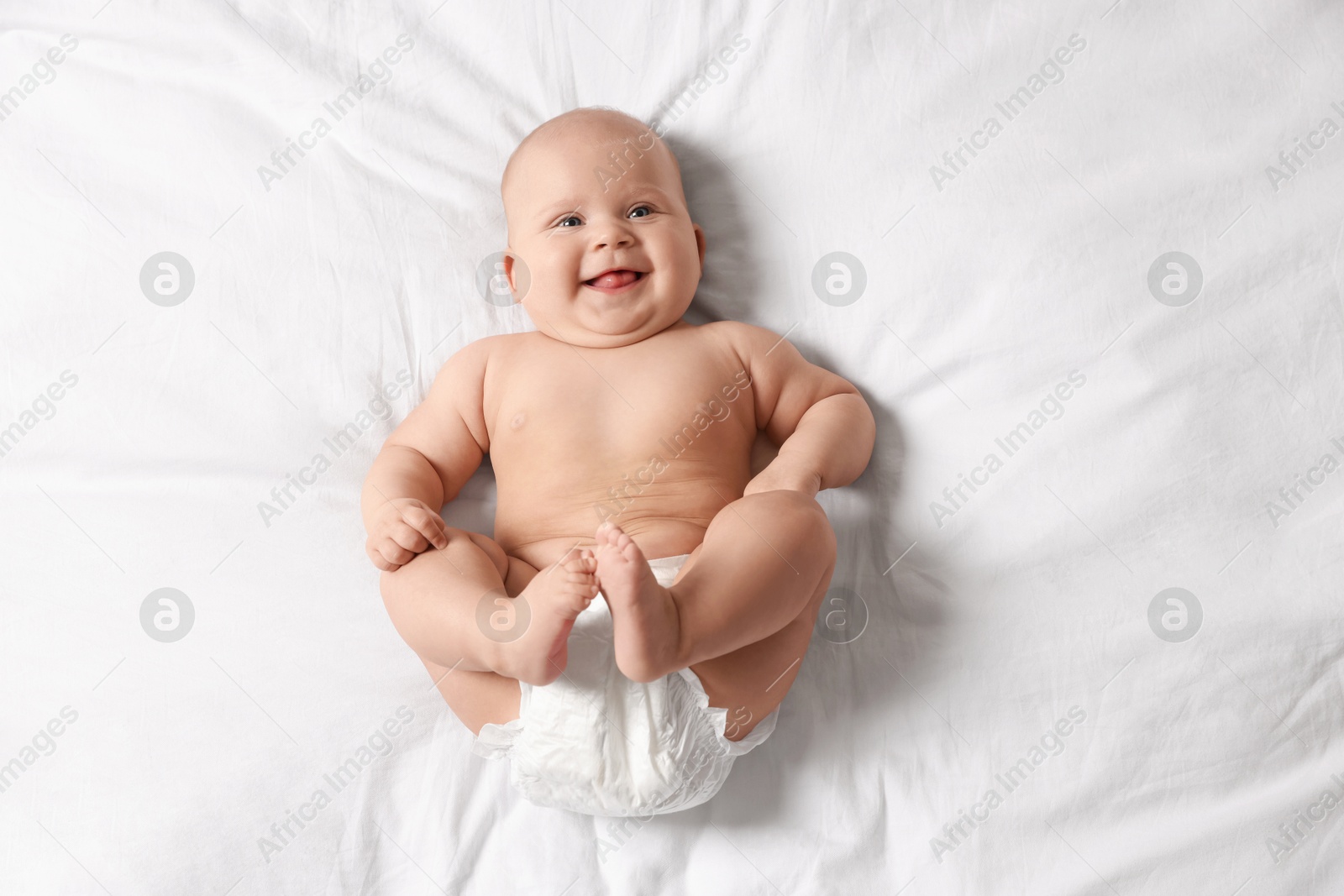 Photo of Cute little baby in diaper on bed, top view