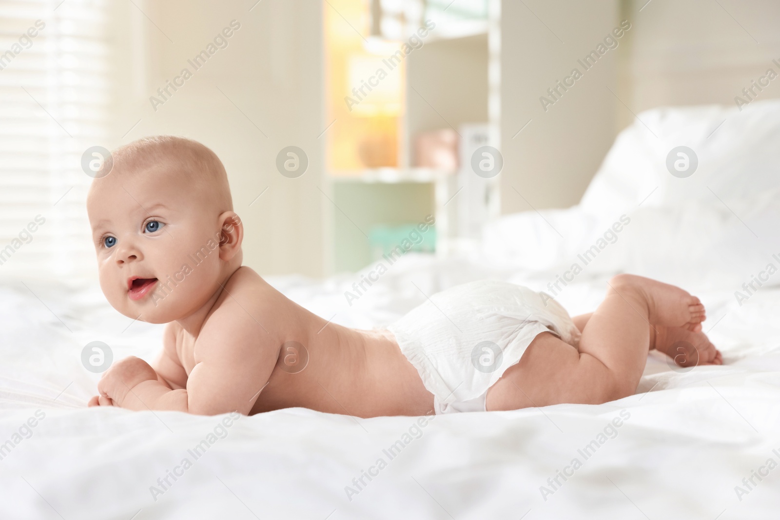 Photo of Cute little baby in diaper on bed indoors