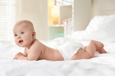 Photo of Cute little baby in diaper on bed indoors