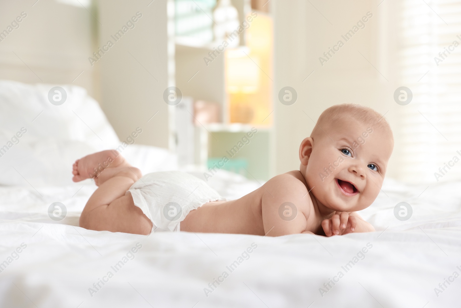 Photo of Cute little baby in diaper on bed indoors