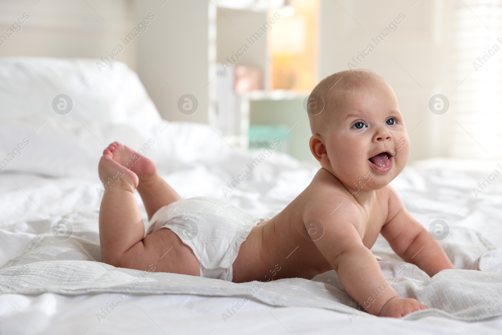 Photo of Cute little baby in diaper on bed indoors