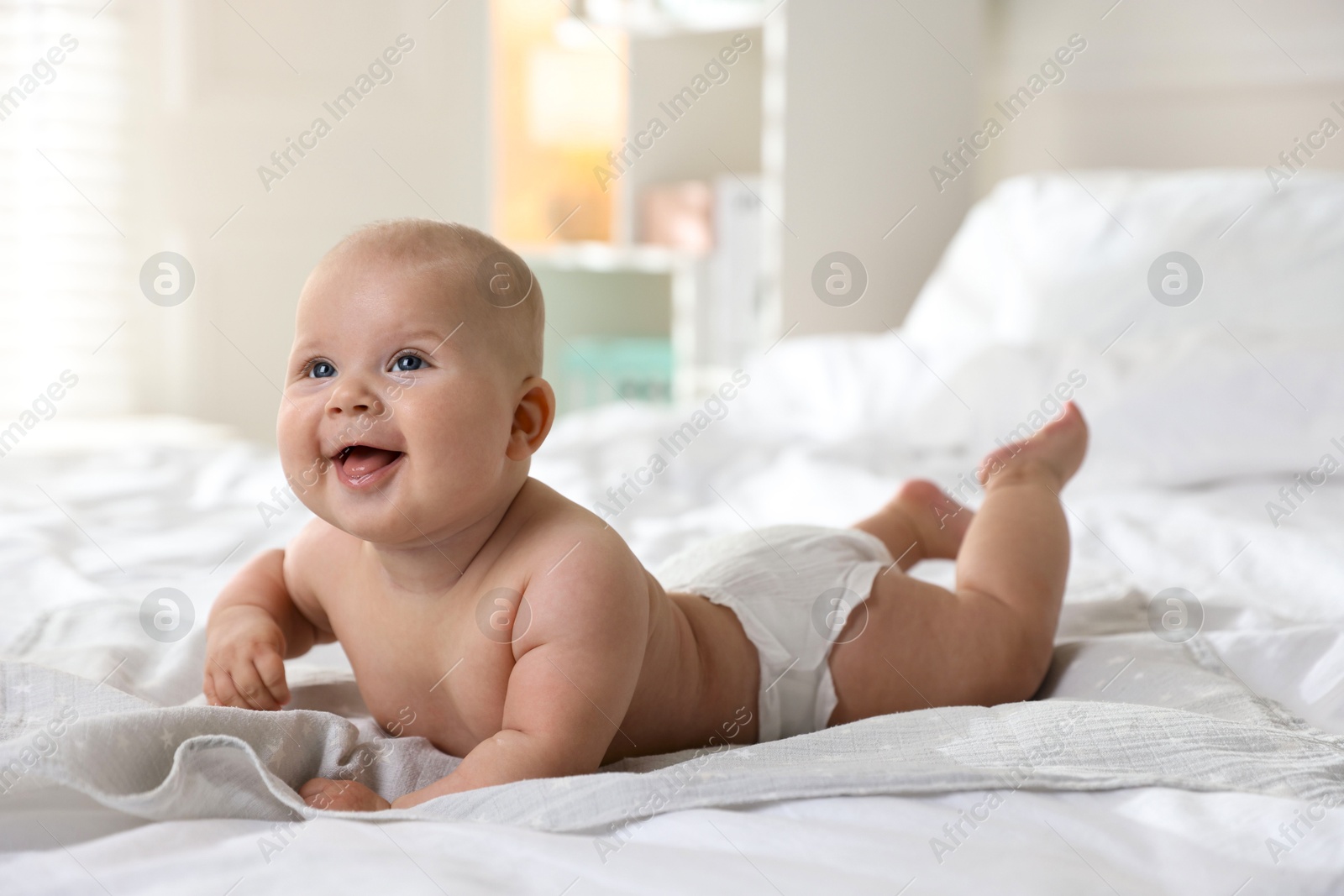 Photo of Cute little baby in diaper on bed indoors