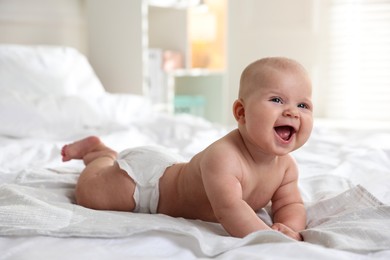 Photo of Cute little baby in diaper on bed indoors