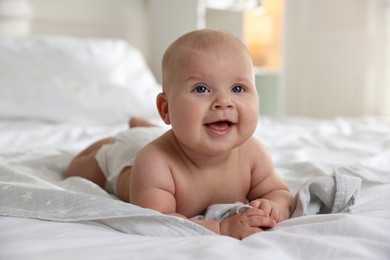 Photo of Cute little baby in diaper on bed indoors