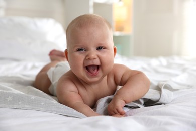 Photo of Cute little baby in diaper on bed indoors