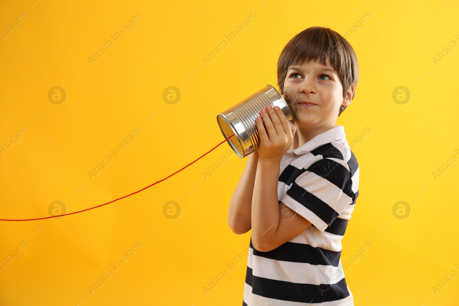 Photo of Boy using tin can telephone on yellow background