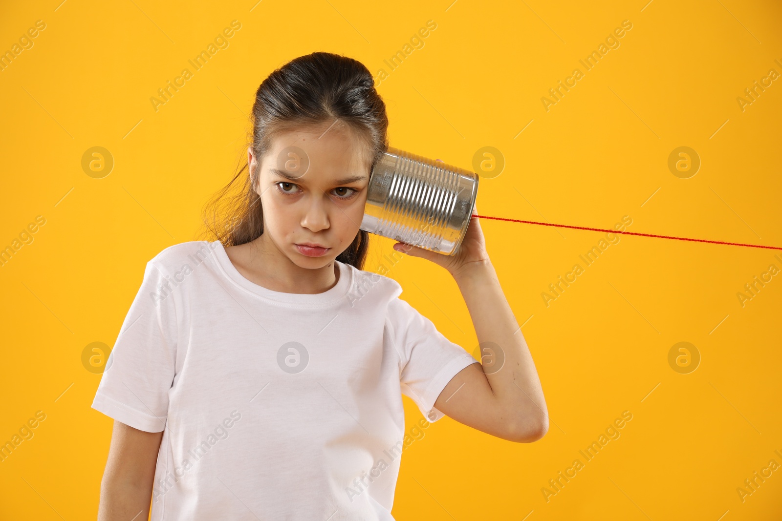 Photo of Girl using tin can telephone on yellow background