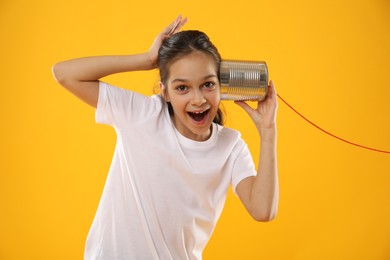 Photo of Girl using tin can telephone on yellow background