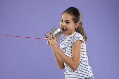 Photo of Girl using tin can telephone on violet background