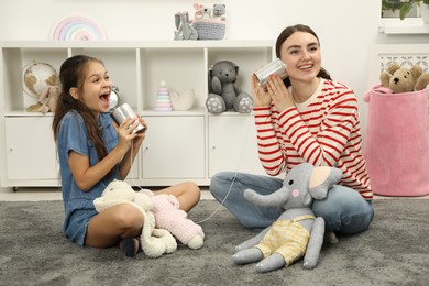 Photo of Woman and girl talking on tin can telephone indoors