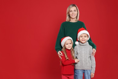 Photo of Mother and her little children on red background, space for text. Christmas season